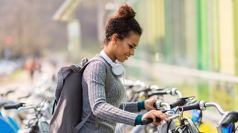 a smiling student parks a bike