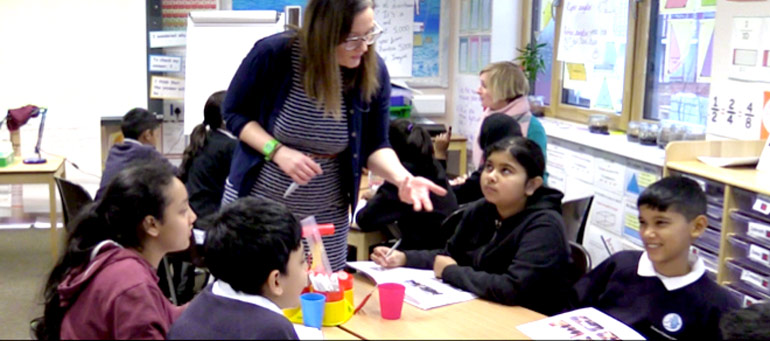 A teacher talks to a table of children listening