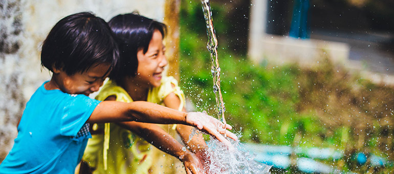 Two children playing with water - unsplash