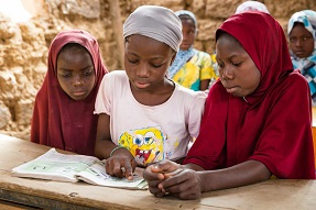Girls in classroom looking at a book Niger