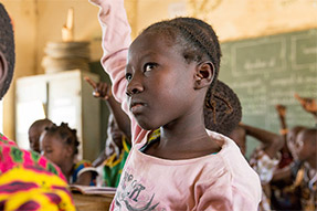 An african girl in class with hand in the air