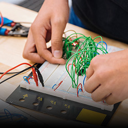 A school childs hands works on an electronic circuit board