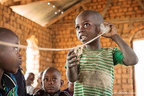 A young boy plays with a home-made tincan telephone in a rural classroom