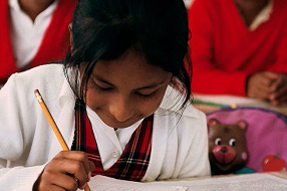 Girl sits at desk in class writing