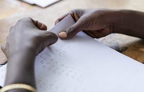 A student's hands reading Braille on paper