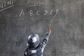 Boy writes English letters on the blackboard in Ethiopia