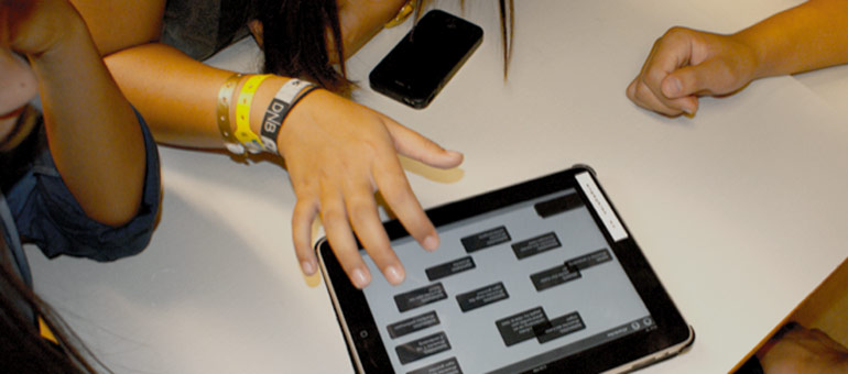 Hands of people sat around a desk using a tablet