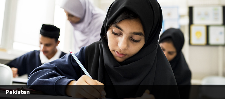 young Muslim female student writing in a classroom