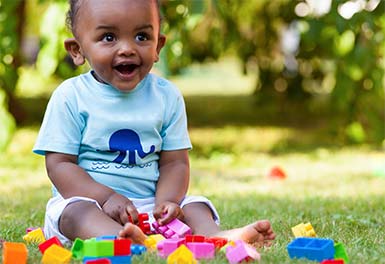 child on grass playing with blocks