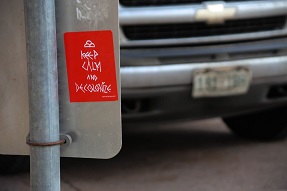 Sticker on a road sign saying 'Keep Calm and Decolonize'
