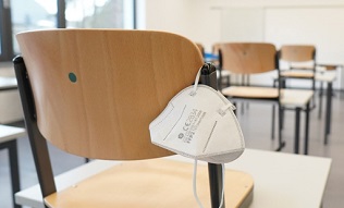 Face mask hanging behind chair in classroom