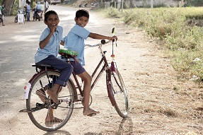 Two children in school uniform on a bike in India