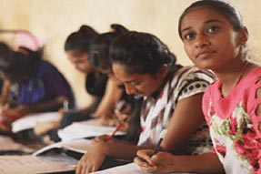 Girls sitting on floor studying in a classroom, India