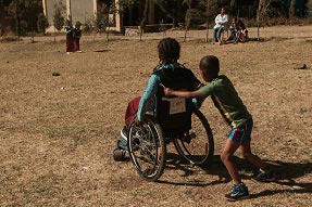 A student pushes his classmate in a wheelchair in the school yard