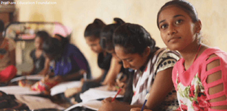 Girls sitting on floor studying in a classroom, India