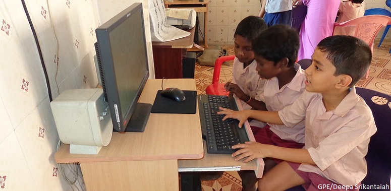 Three students on the computer in primary school in Tamil Nadu, India