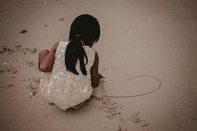 Young girls plays in the sand, India