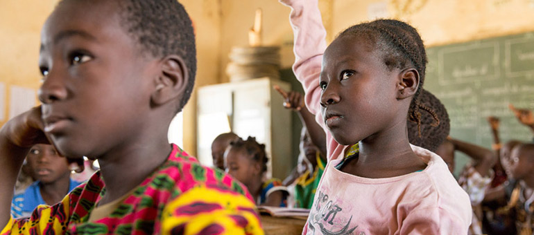 African girl in class with hand in the air