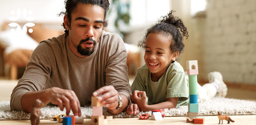 Imaginery play - a dad with building blocks, toy cars and figures playing with his daughter on the living room floor